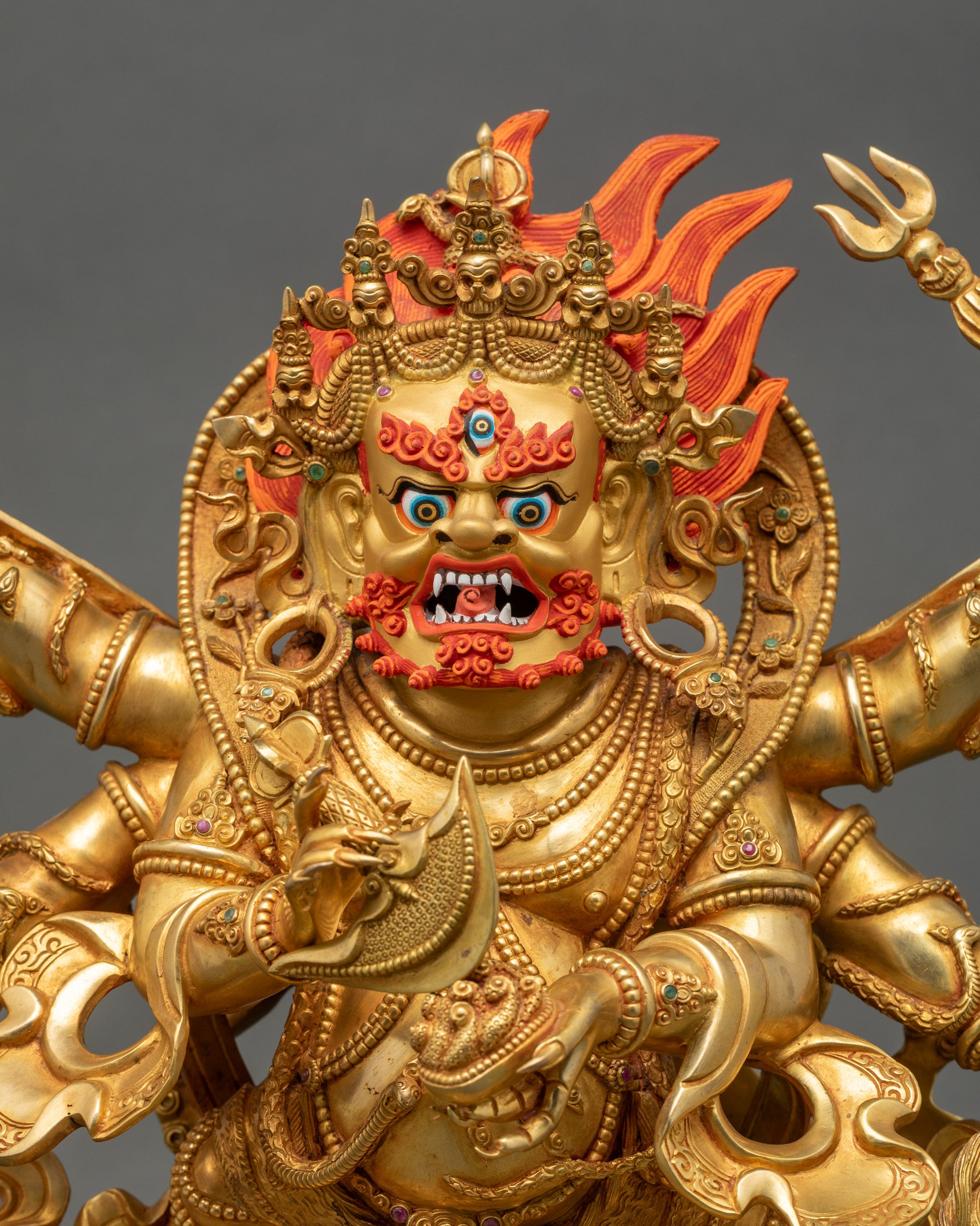 Close-up of handcrafted Mahakala statue showing gold-gilded face, intricate robes, skull garland