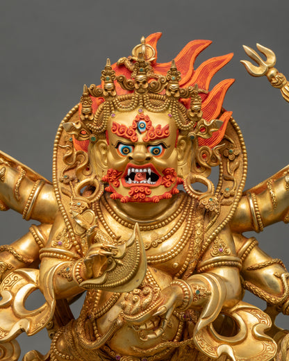 Close-up of handcrafted Mahakala statue showing gold-gilded face, intricate robes, skull garland