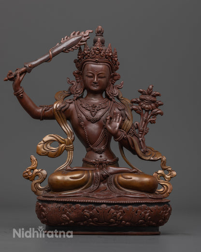 Oxidized Manjushri statue seated on a lotus throne, holding a flaming sword and a scripture, symbolizing the cutting of ignorance and the embodiment of wisdom.