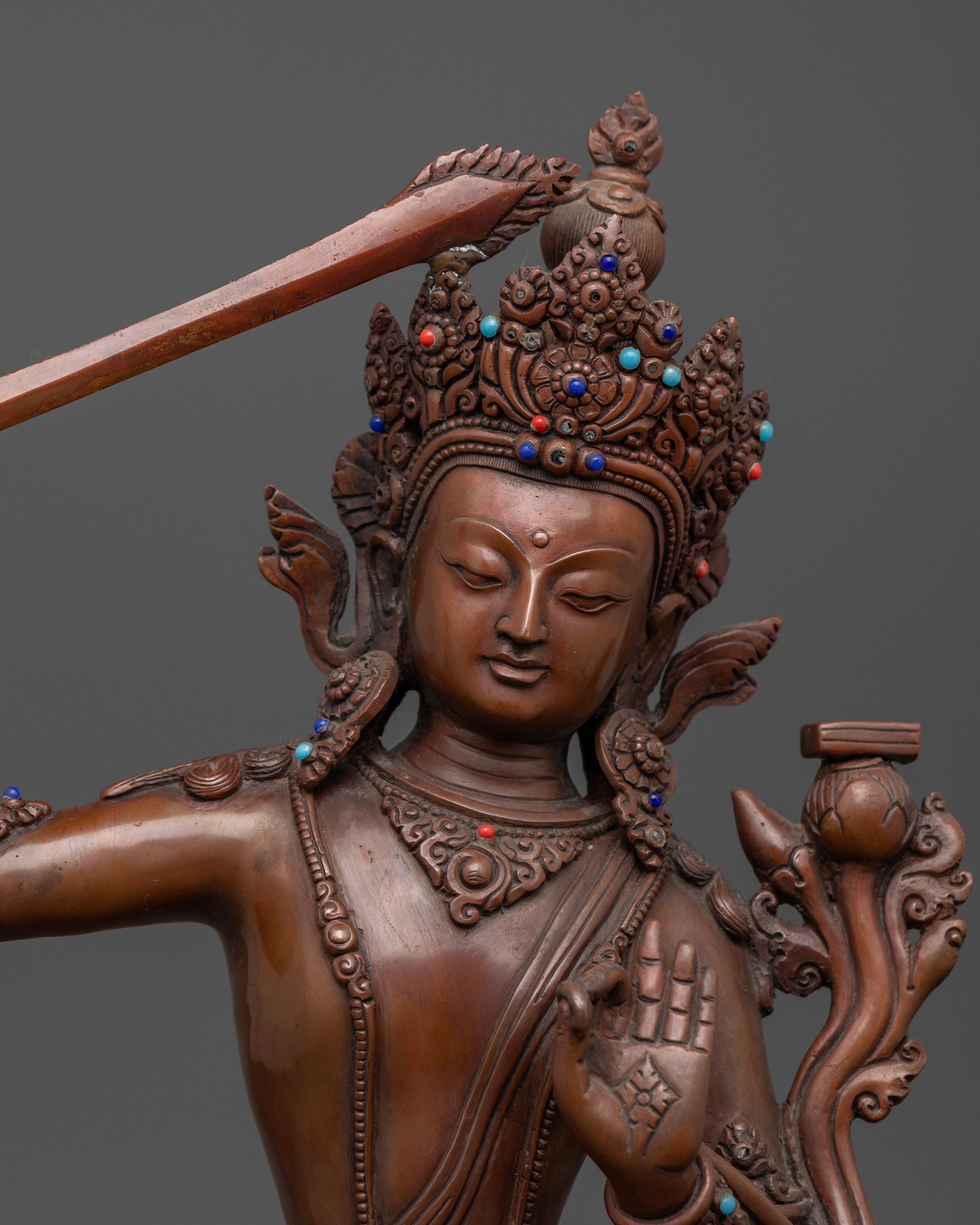 The Manjushri statue featuring a flaming sword in the right hand and a scripture in the left, representing the cutting of ignorance and cultivation of wisdom.