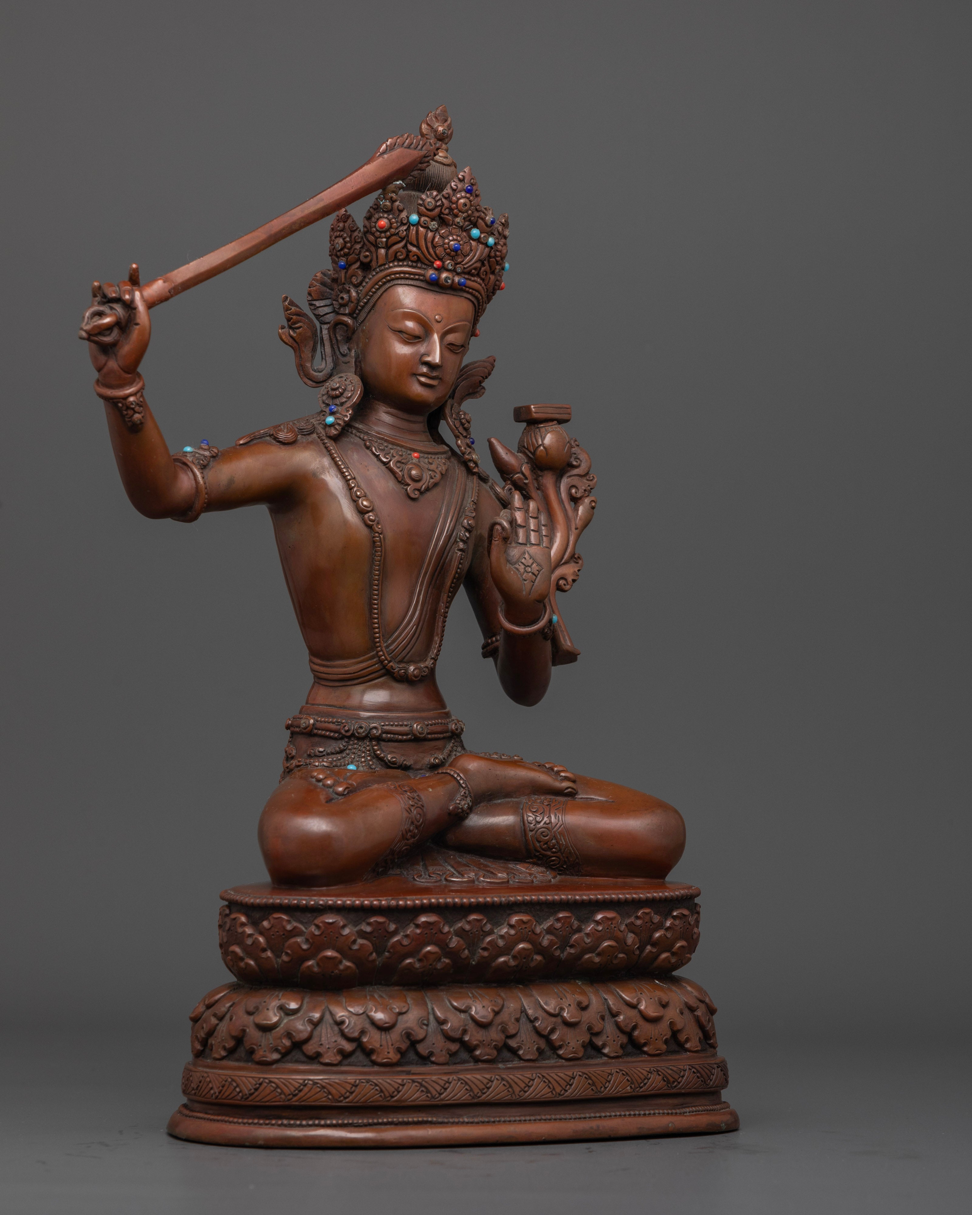 The oxidized Manjushri statue, highlighting fine craftsmanship, semi-precious stone decorations, and symbolic spiritual elements.

