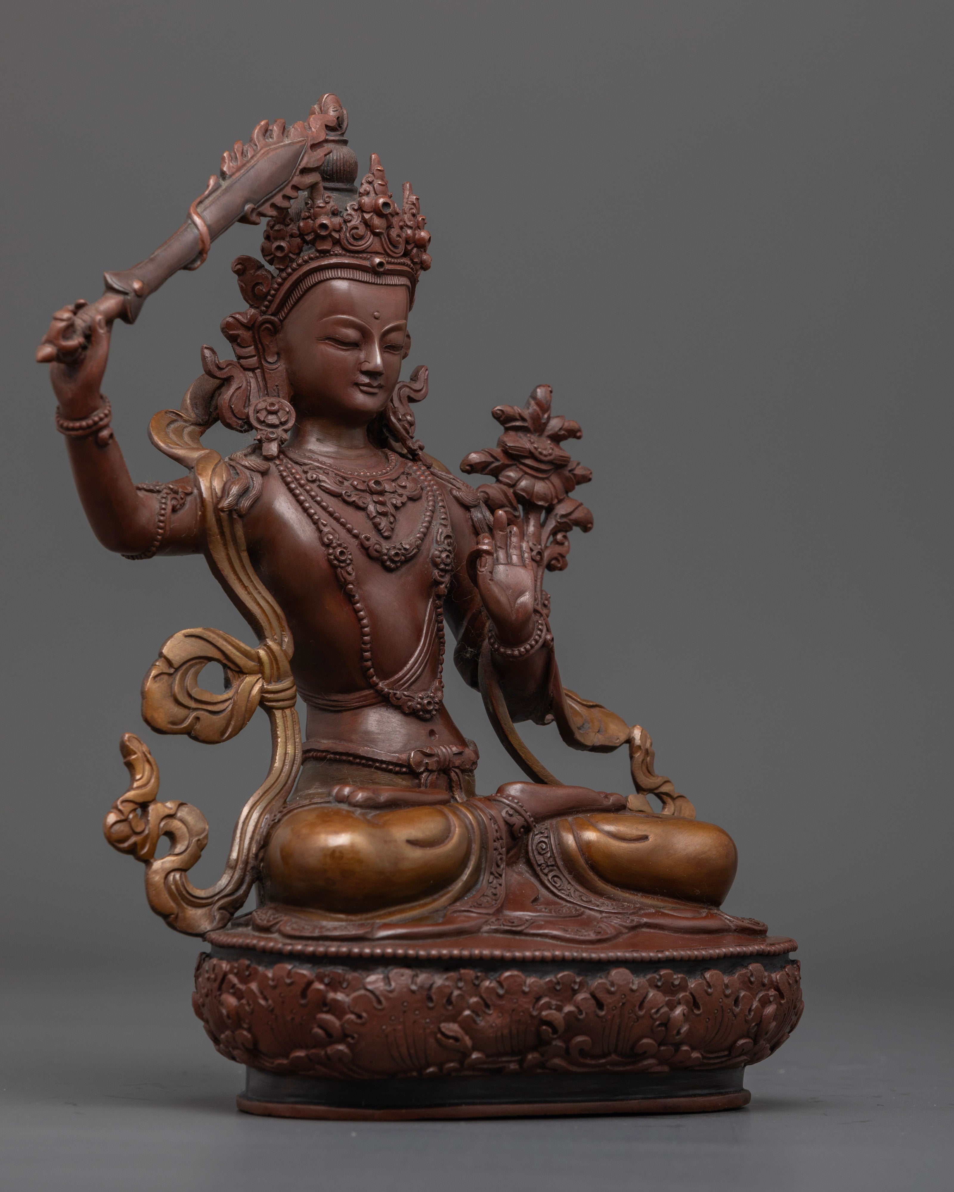The oxidized copper Manjushri statue, featuring intricate designs and the symbolic lotus throne representing purity and enlightenment.