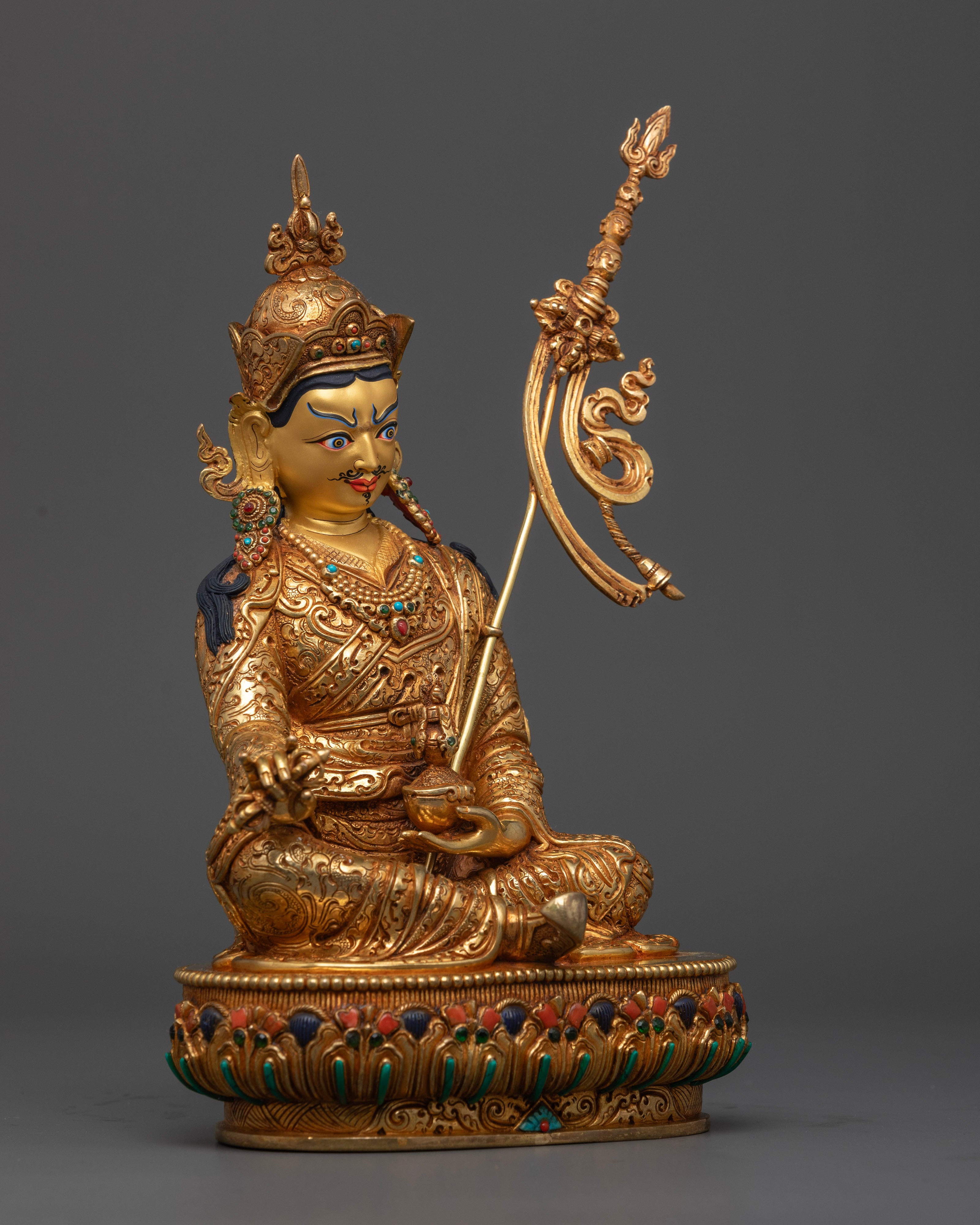 The statue displaying the symbolic trident resting on Guru Rinpoche’s left shoulder, representing mastery over obstacles and spiritual challenges.

