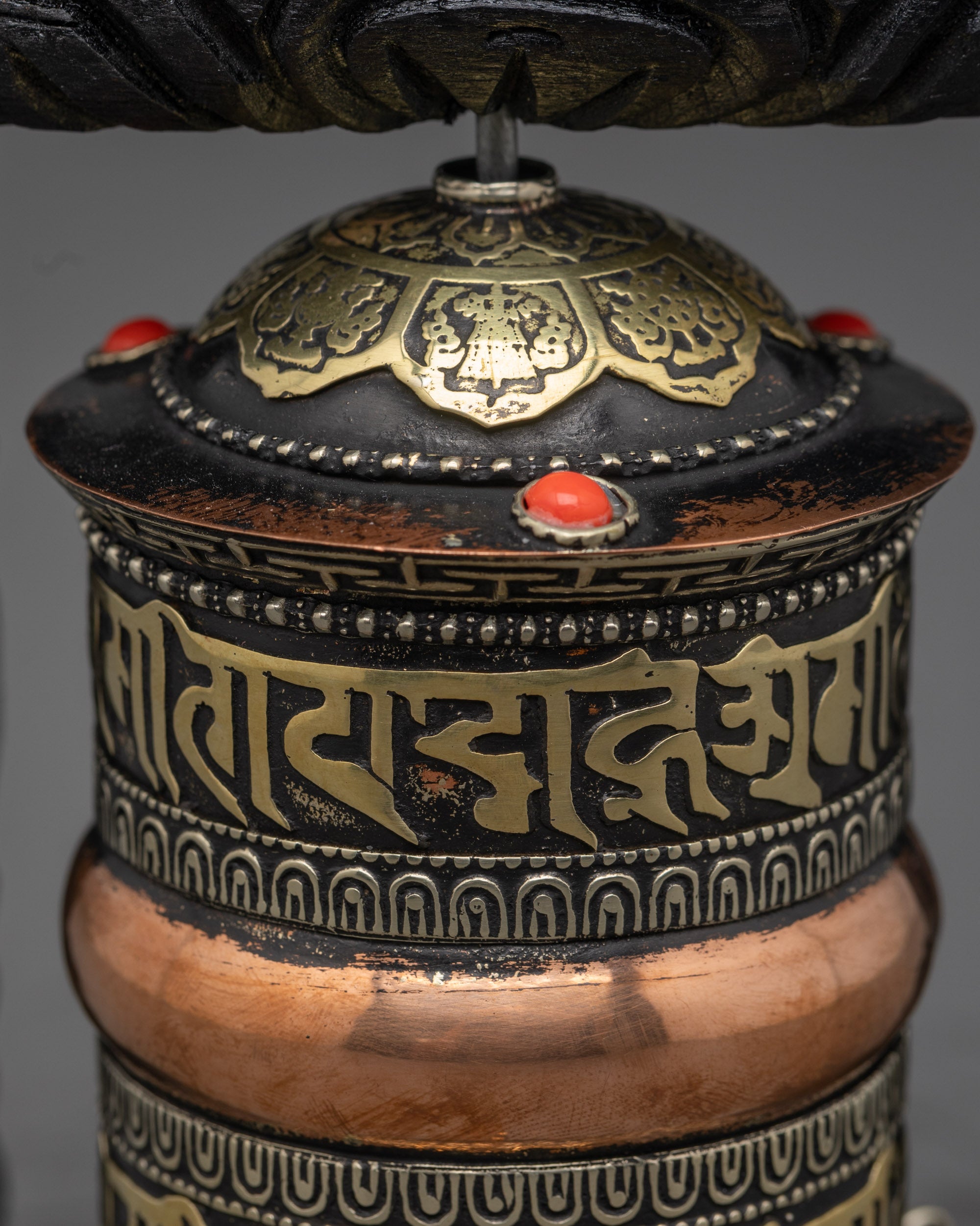 Top view of bronze-finished copper prayer wheel with sacred carvings and details
