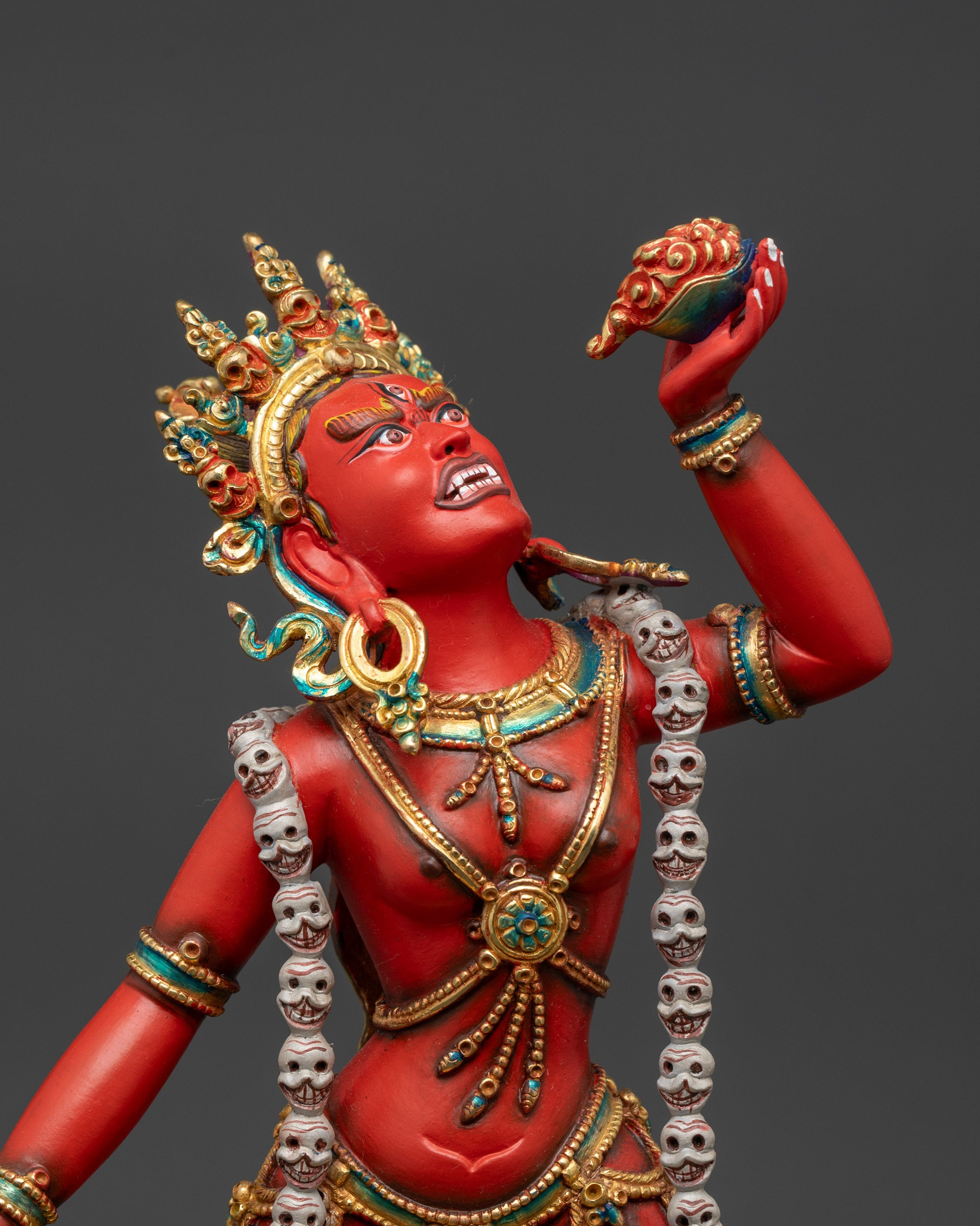 Vajrayogini's red hued body with five skull crown and sacred ritual tools.

