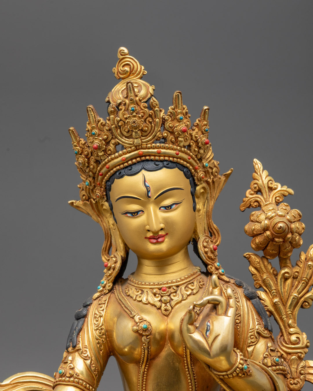 White Tara bodhisattva statue holding lotus, featuring hollow base for sacred mantra, adorned with semi-precious stones and vibrant colors.