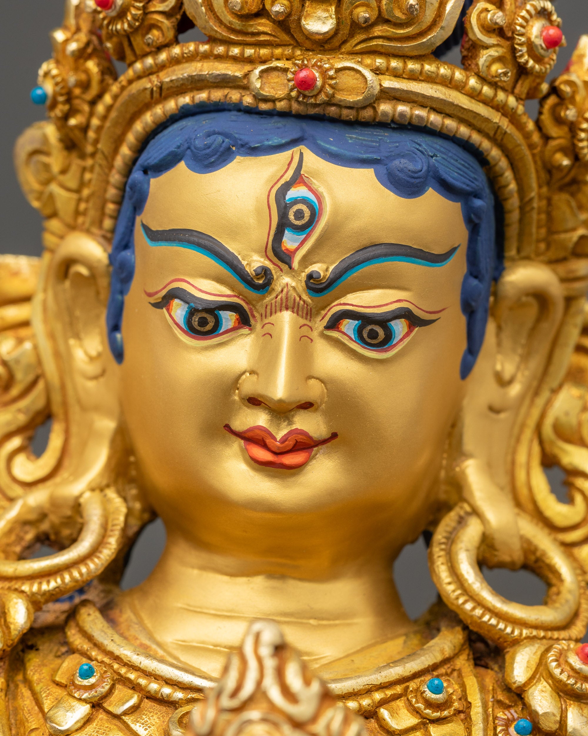 Gold gilded face of Achi Chokyi Drolma statue with sacred third eye and serene expression