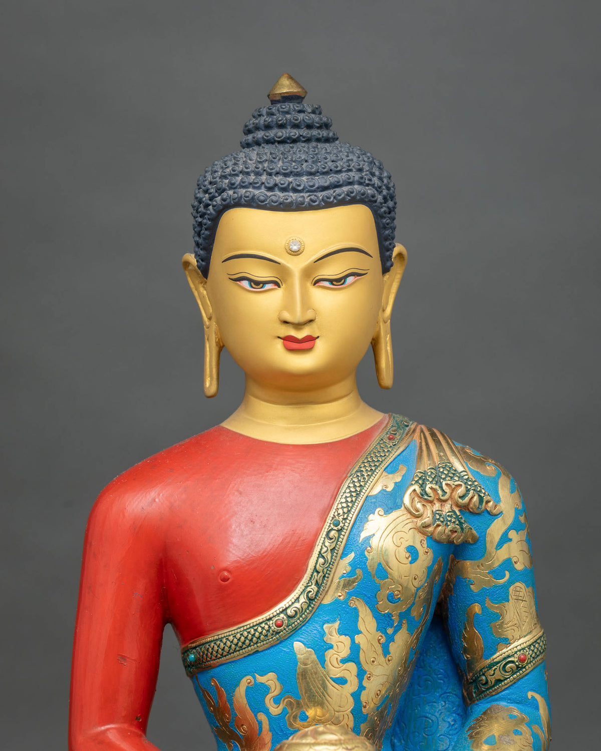 Amitabha Buddha statue close up with gold painted face and contemplative eyes.