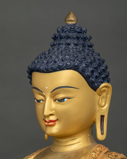 Angled close-up of Buddha Shakyamuni statue face with painted eyes, ushnisha and elongated ears