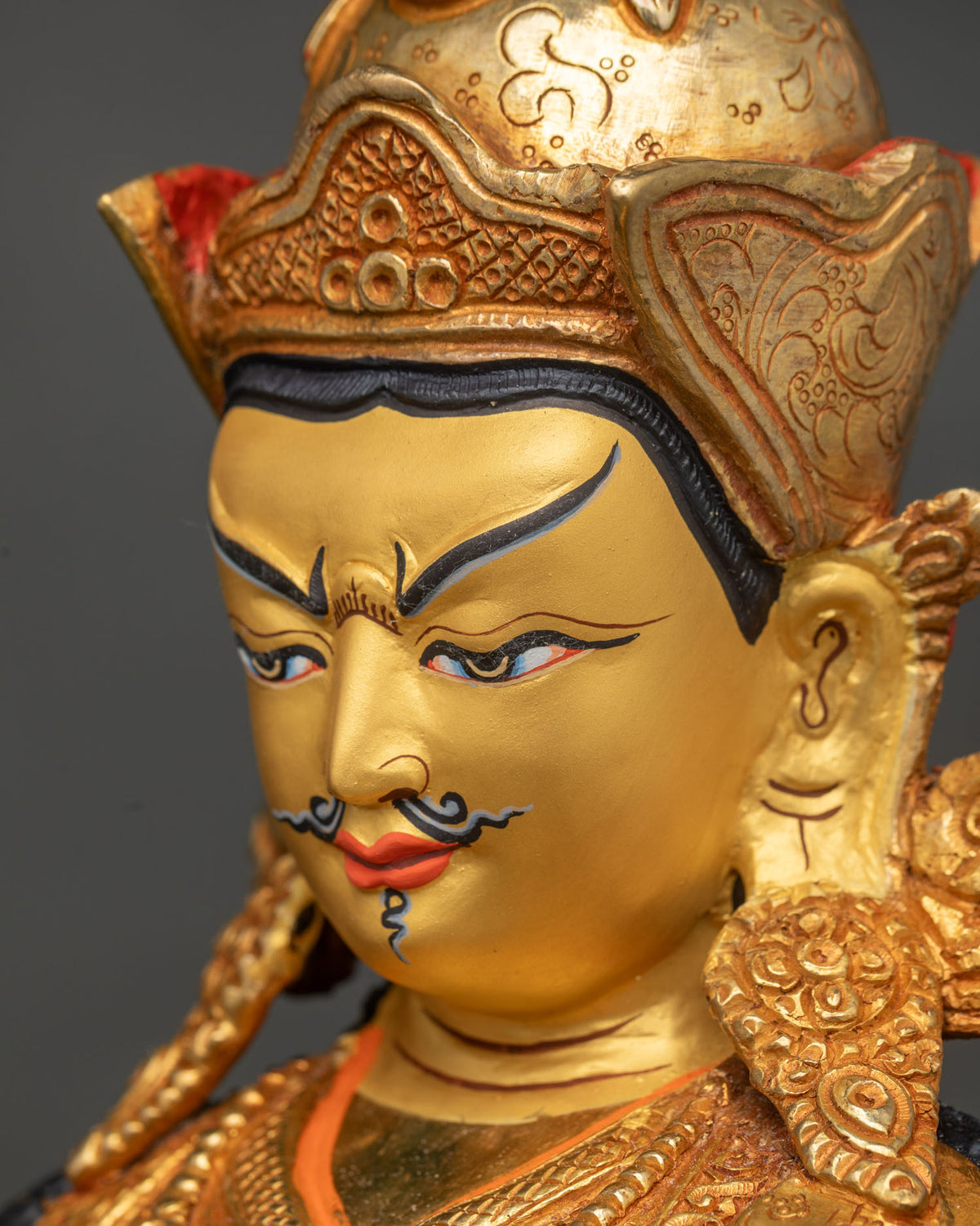 Angled close-up of handmade Tsokye Dorje statue face, crown and 24K gold gilding