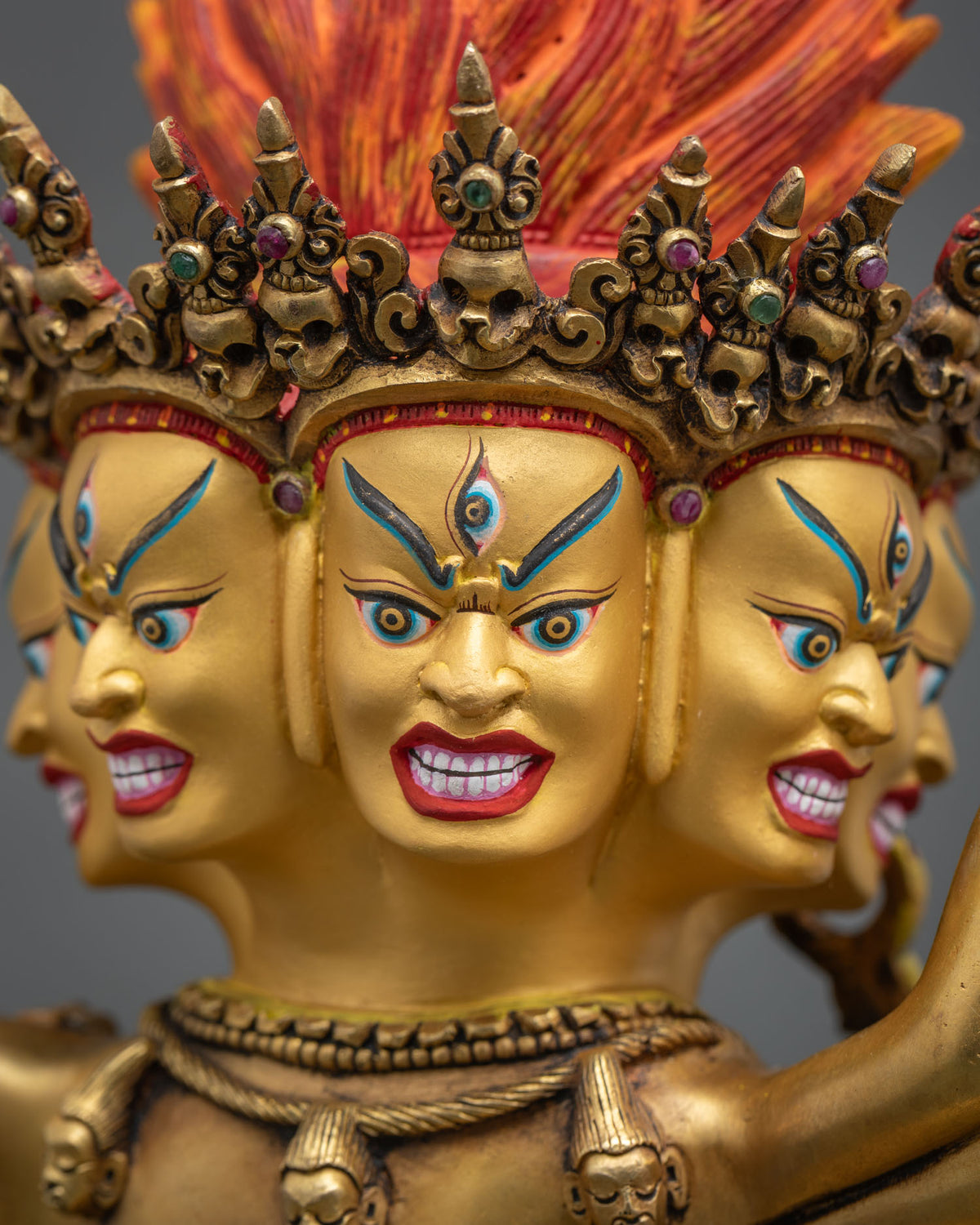 Angled close-up of Hevajra’s faces with jeweled skull crown and necklace, hand-carved copper