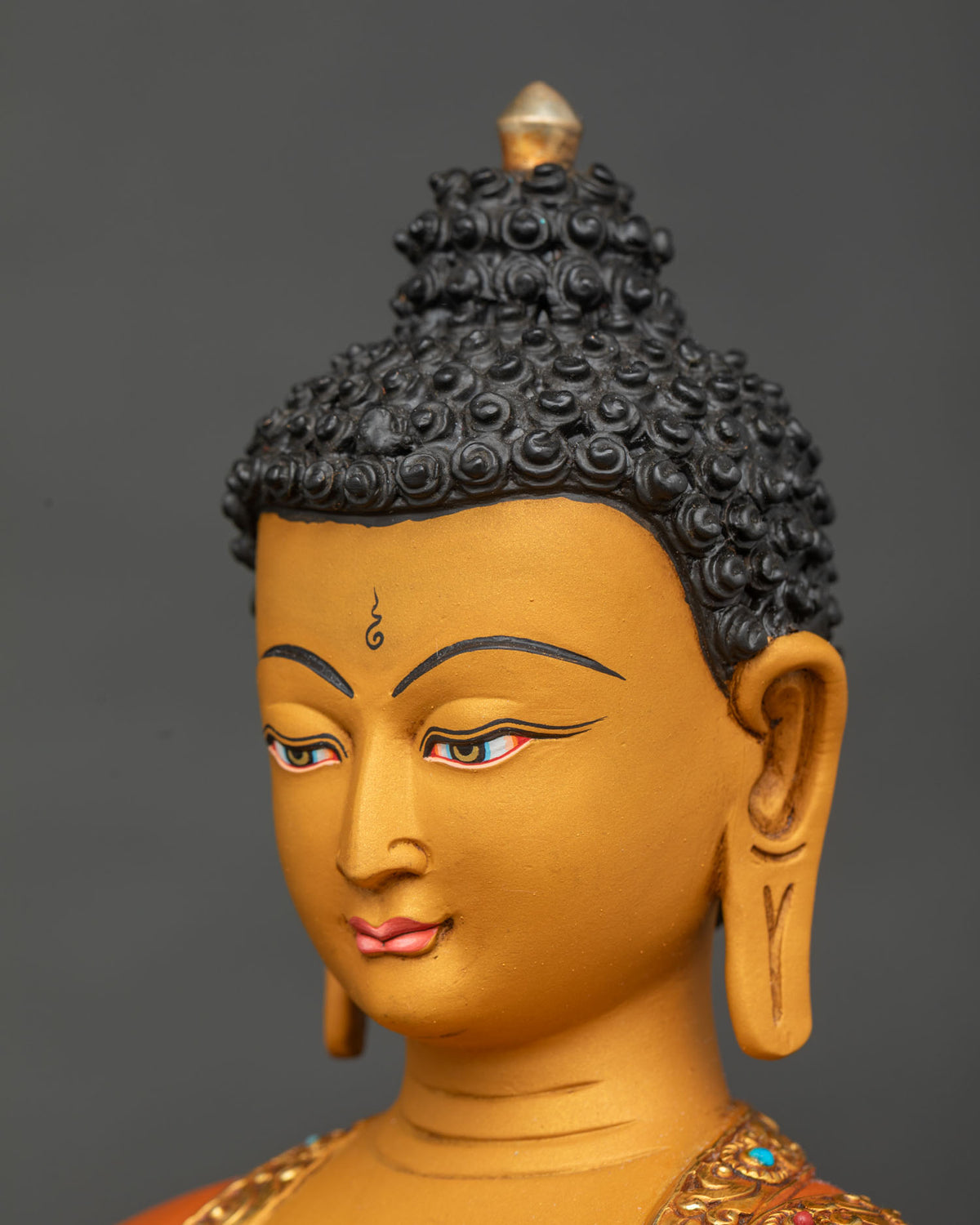 Angled close-up of Nepalese Buddha statue head with curled hair, urna and elongated ears