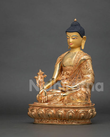 Angled side view of fire-gilded Medicine Buddha holding myrobalan stem and nectar bowl
