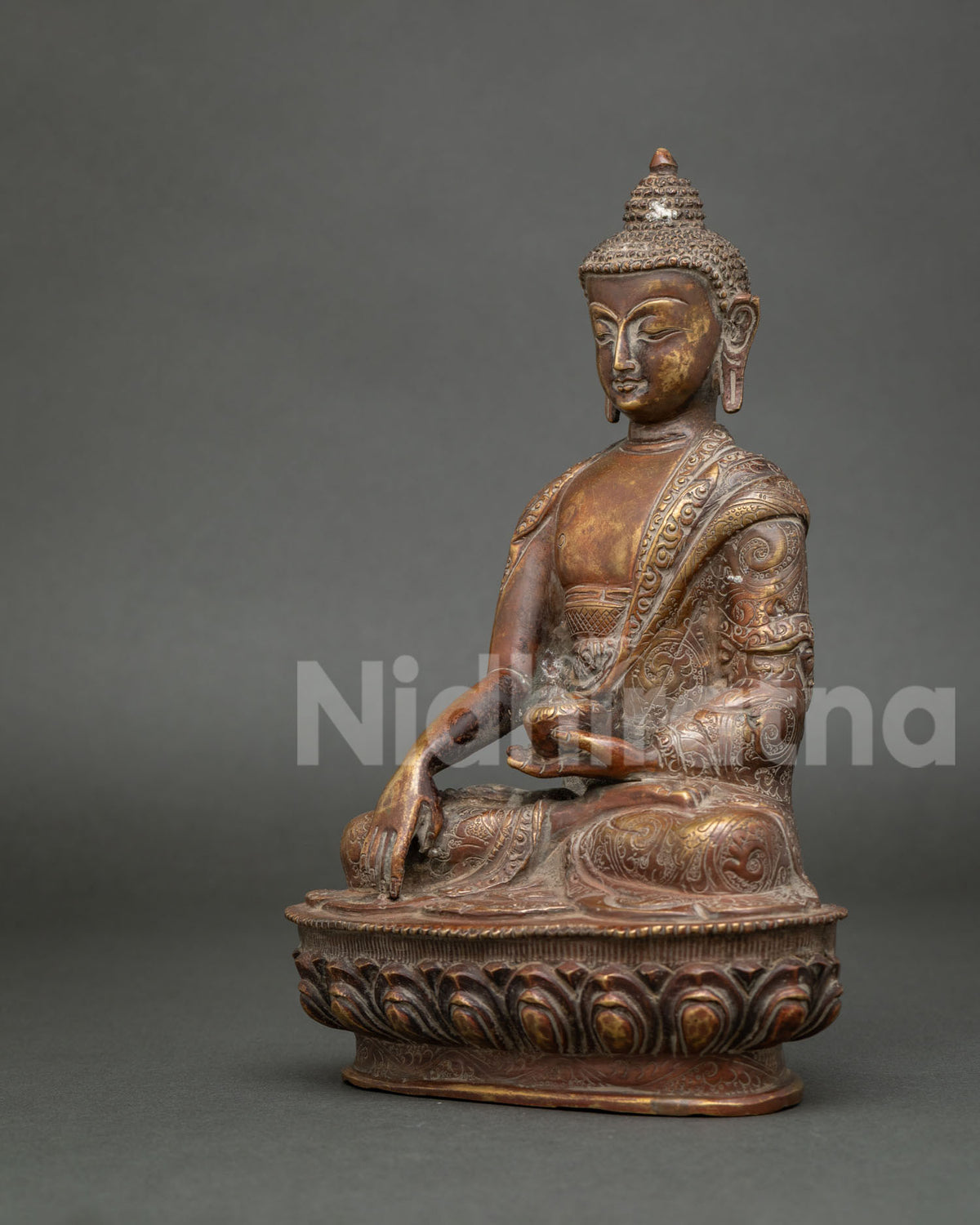 Angled view of antique-finish Shakyamuni Buddha sculpture with detailed robes and traditional Buddhist iconography.