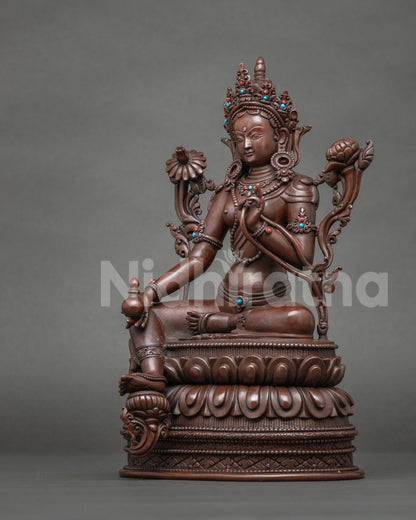 Angled view of Green Tara statue holding a vase on lotus seat