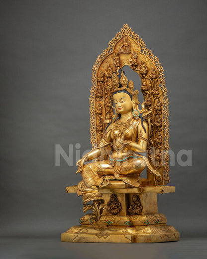 Angled view of Green Tara statue in royal ease with extended right leg and gold fire gilding