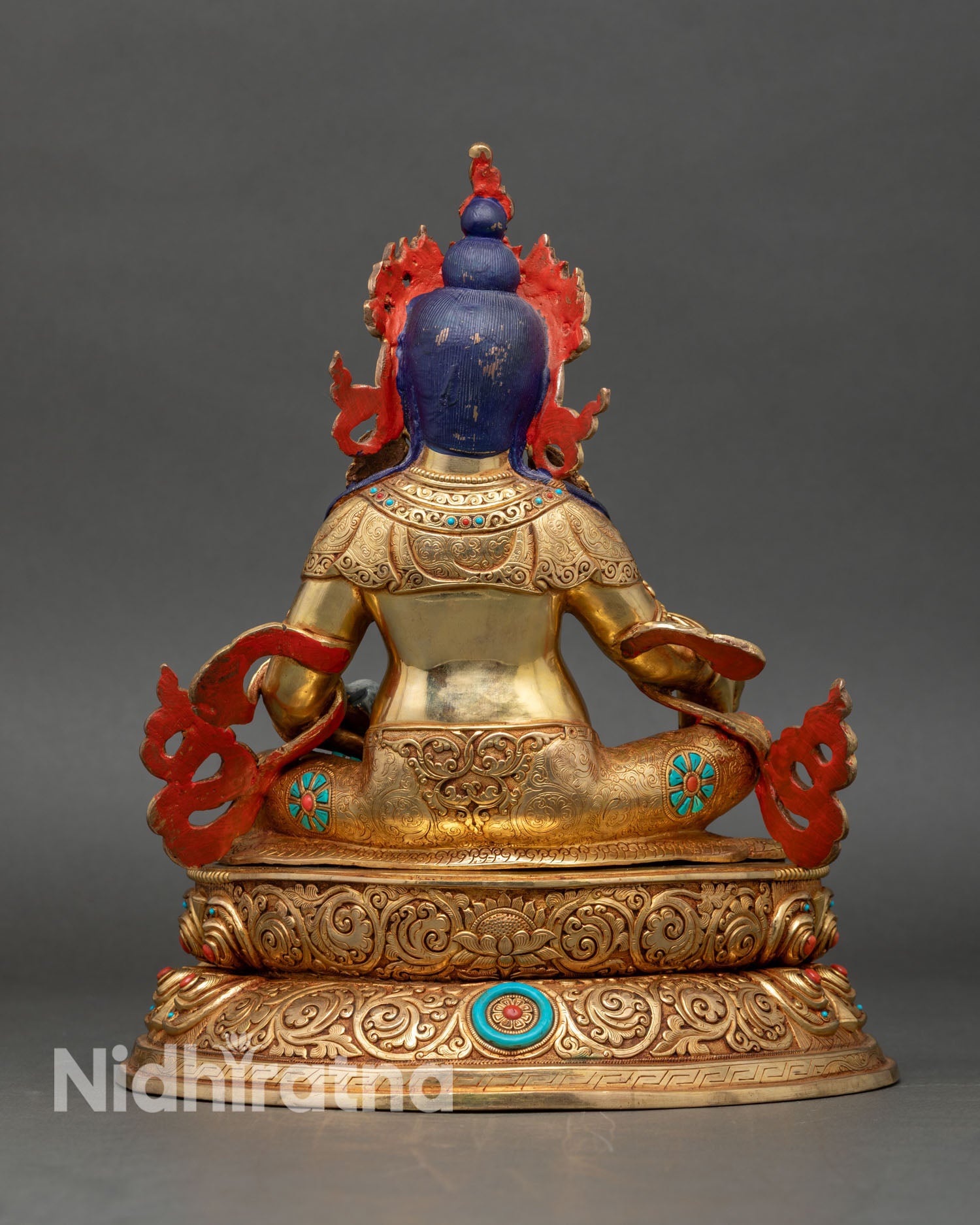 Back view of Dzambhala statue, lotus seat and engraved traditional patterns