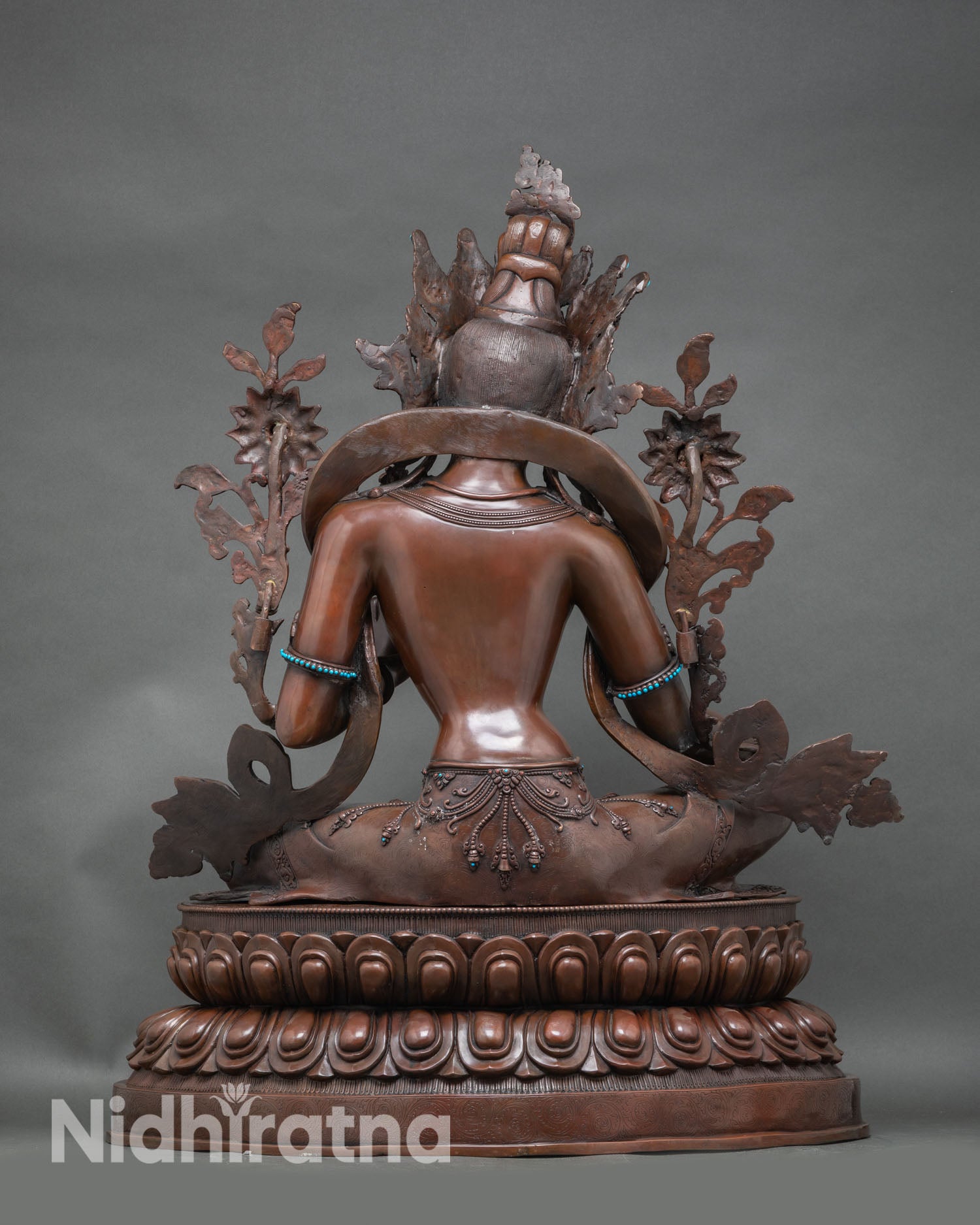 Back view of Green Tara statue showing carved lotus pedestal and flowing robe details