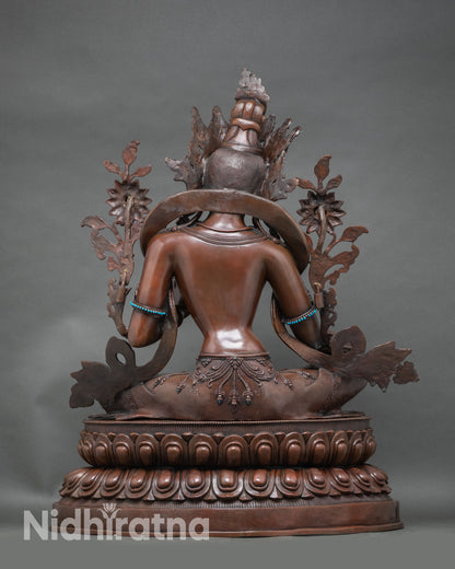 Back view of Green Tara statue showing carved lotus pedestal and flowing robe details