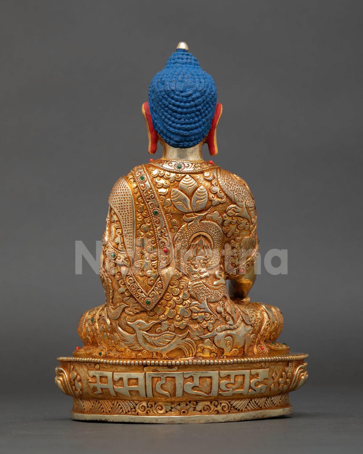 Back view of Nepalese Shakyamuni Buddha statue copper gold gilded finish engraved monastic robe with floral and mythical buddhist motifs