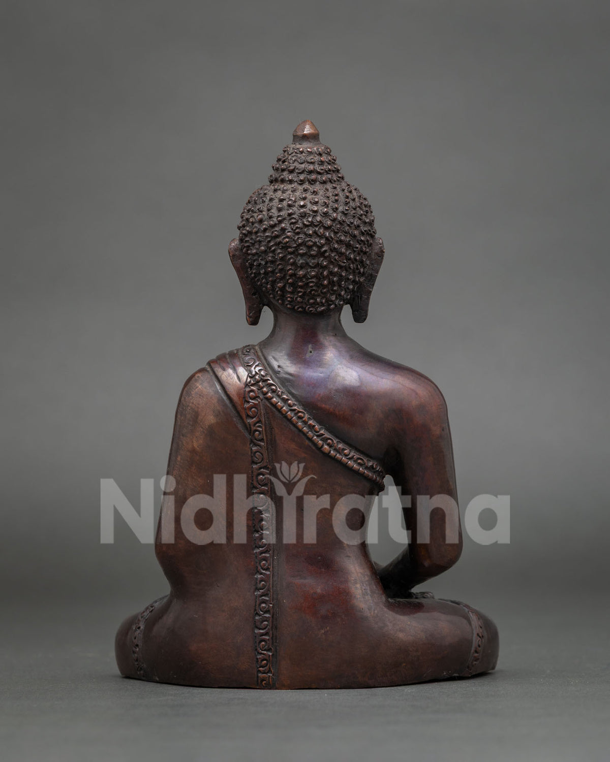 Back view of Amitabha Buddha copper statue showing carved robe trim and oxidized brown finish