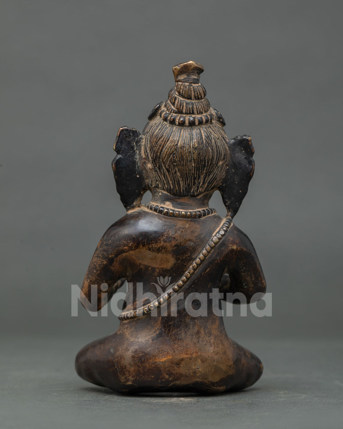 Back view of antique oxidized copper Ganesha statue showing hair bun and beaded shoulder