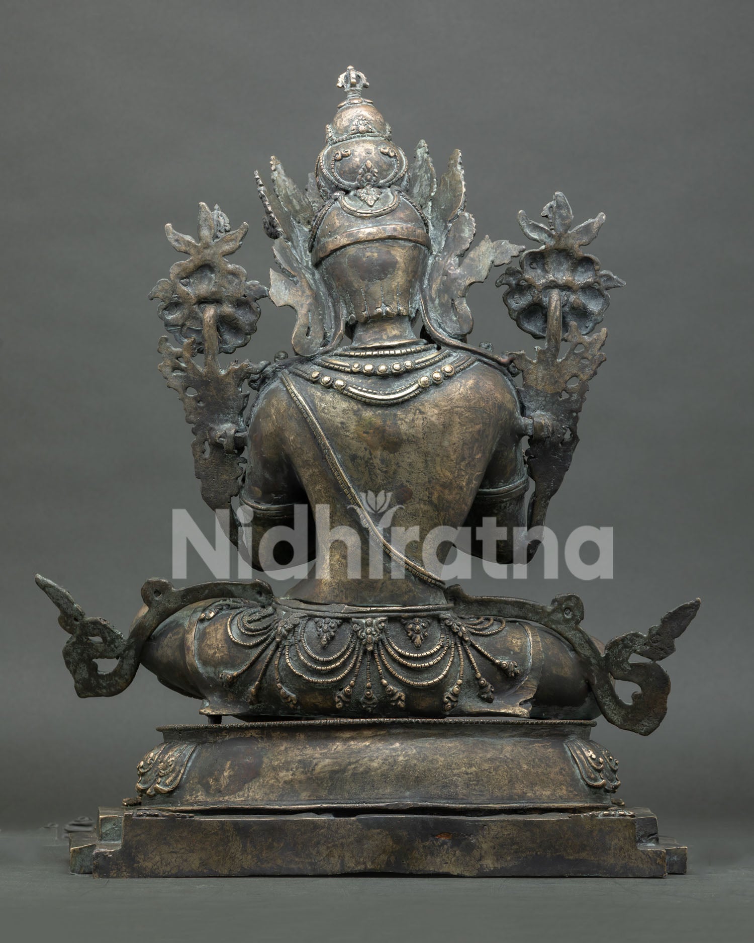 Back view of bronze Vajradhara statue showing crown, jewelry, and lotus seat carving