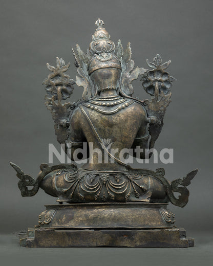 Back view of bronze Vajradhara statue showing crown, jewelry, and lotus seat carving