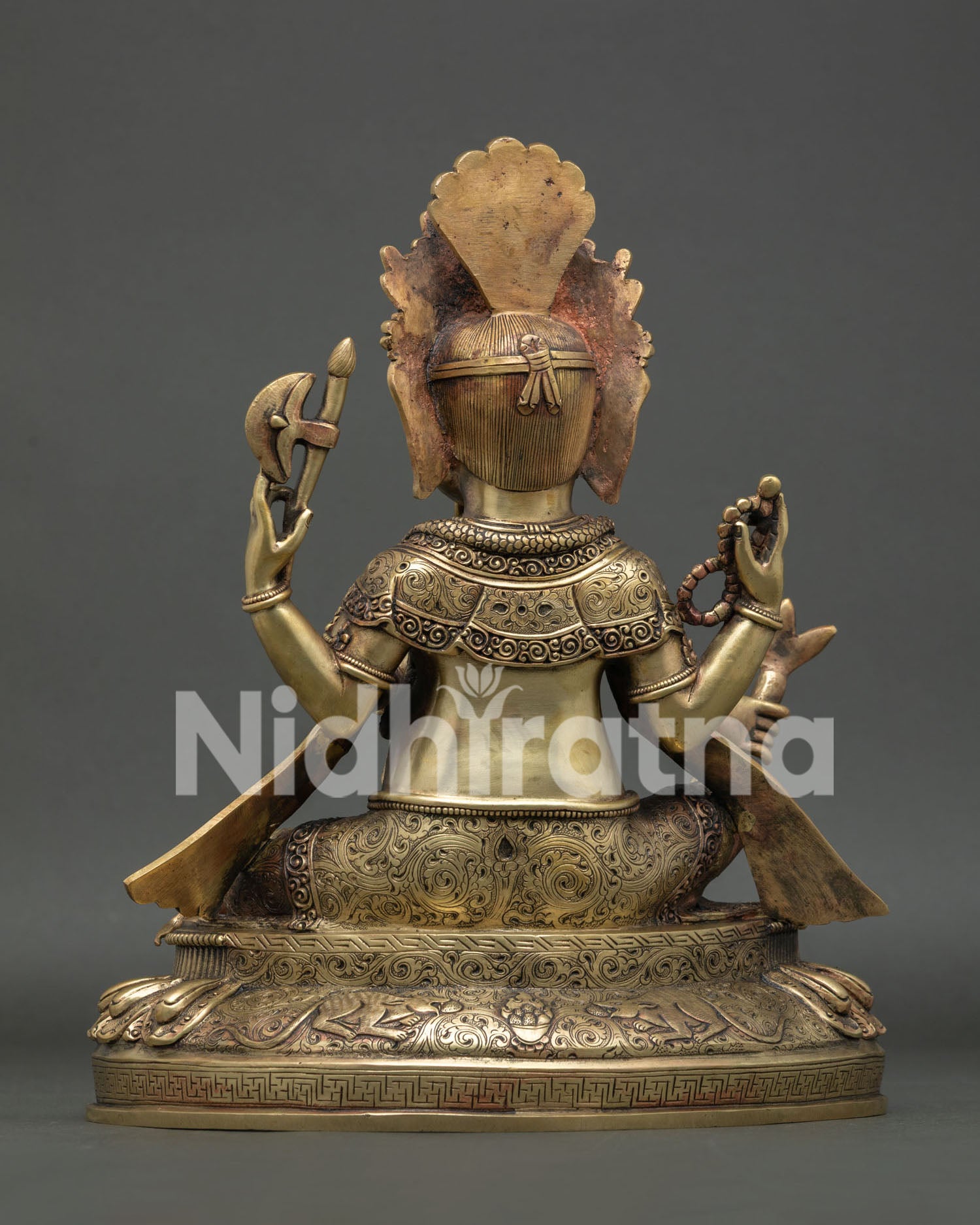 Back view of copper Ganesh statue showing hand-chased detailing and elaborate headdress
