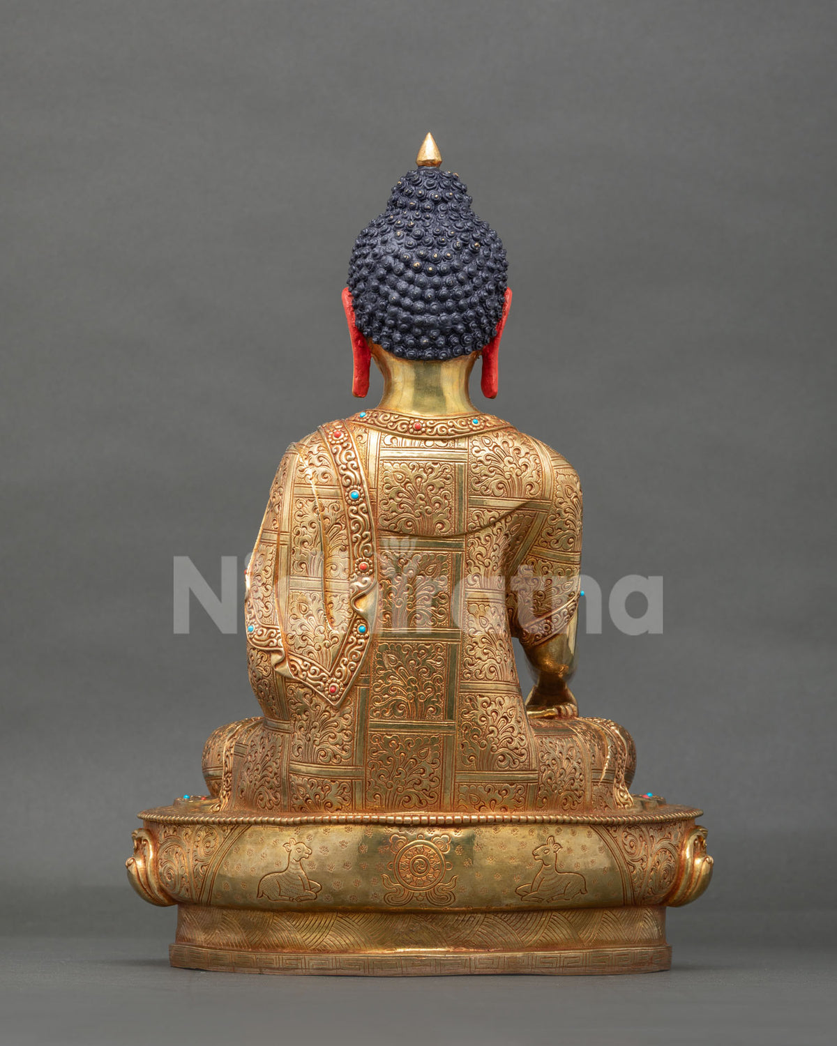 Back view of copper Shakyamuni Buddha statue revealing intricately carved celestial robe motifs.