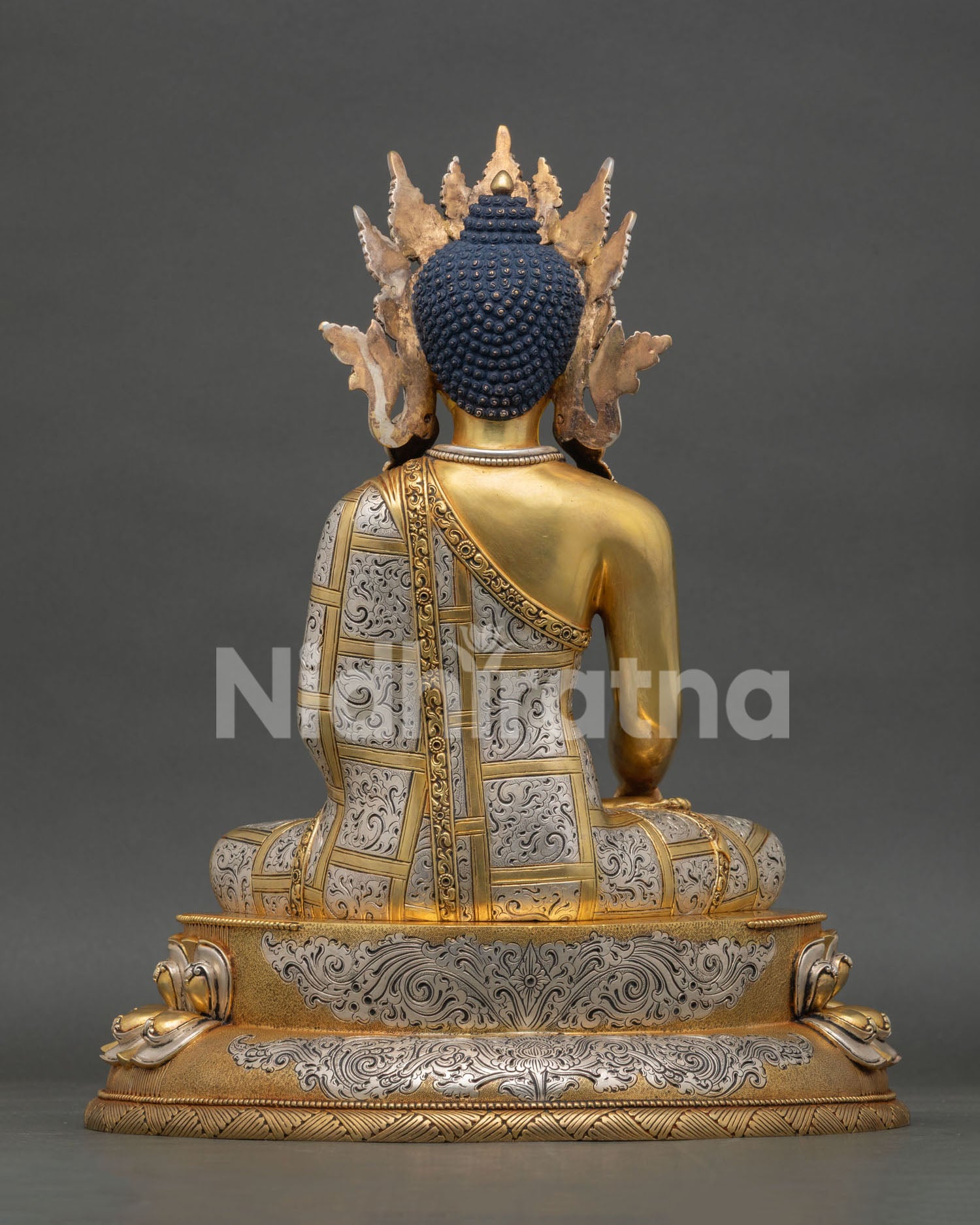 back view of crowned shakyamuni buddha statue with intricate patterns and lotus base details