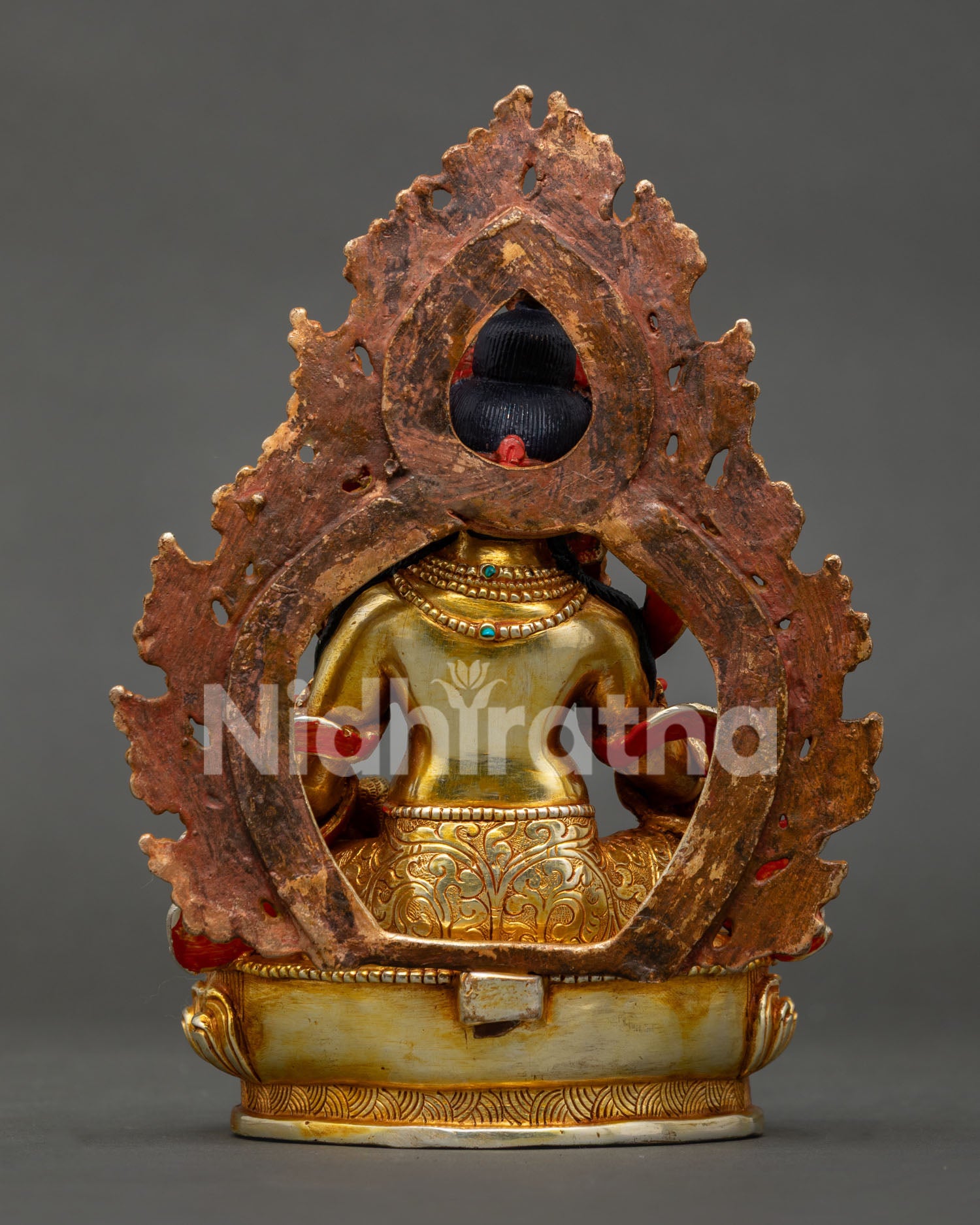 Back view of Dzambhala statue showing detailed lotus pedestal and artisan engraving