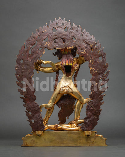 Back view of Ekajati statue showing reddish-brown flame halo backing and gold figure