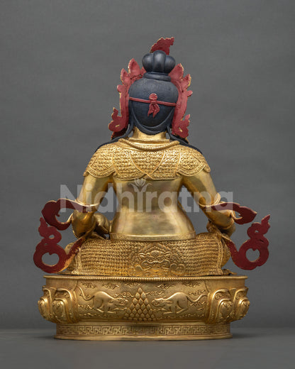 Back view of gold fire-gilded Dzambhala copper statue with engraved robes and lotus base