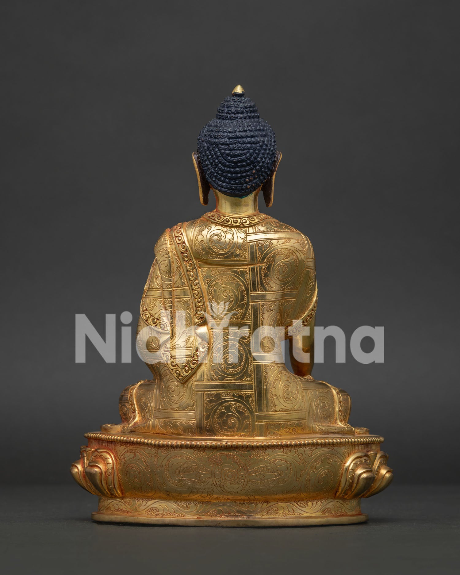 Back view of gold gilded Shakyamuni Buddha statue with intricate monk robe carvings.