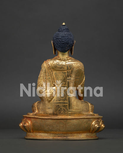 Back view of gold gilded Shakyamuni Buddha statue with intricate monk robe carvings.