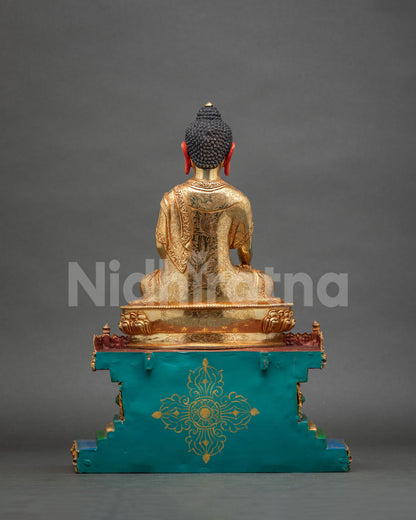 Back view of gold Shakyamuni Buddha with engraved robe and turquoise base featuring gold vajra motif