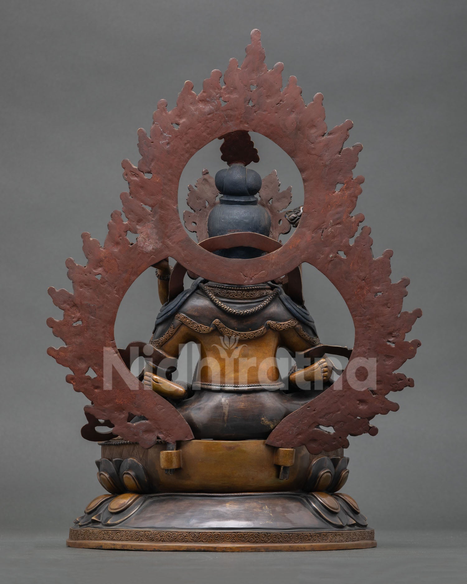 back view of green dzambhala copper statue with carved halo and detailed craftsmanship