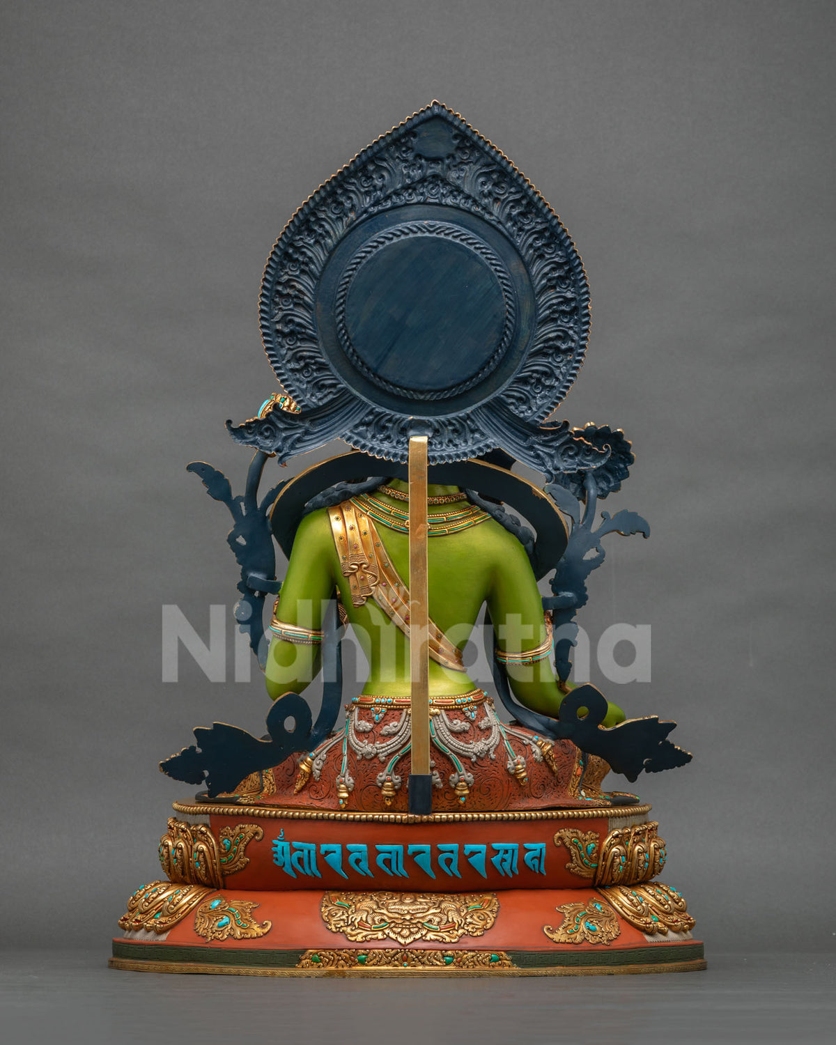 Back view of Green Tara statue with carved blue halo and mantra inscription on lotus base