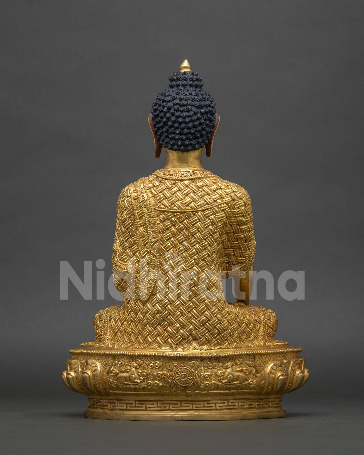 Back view of hand-carved Shakyamuni Buddha statue with detailed robe and lotus base, Nepal
