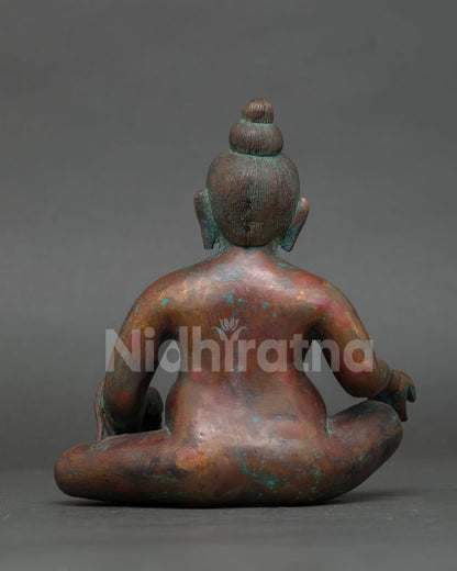 back view of handmade dzambhala statue showing engraved copper artwork and lotus base