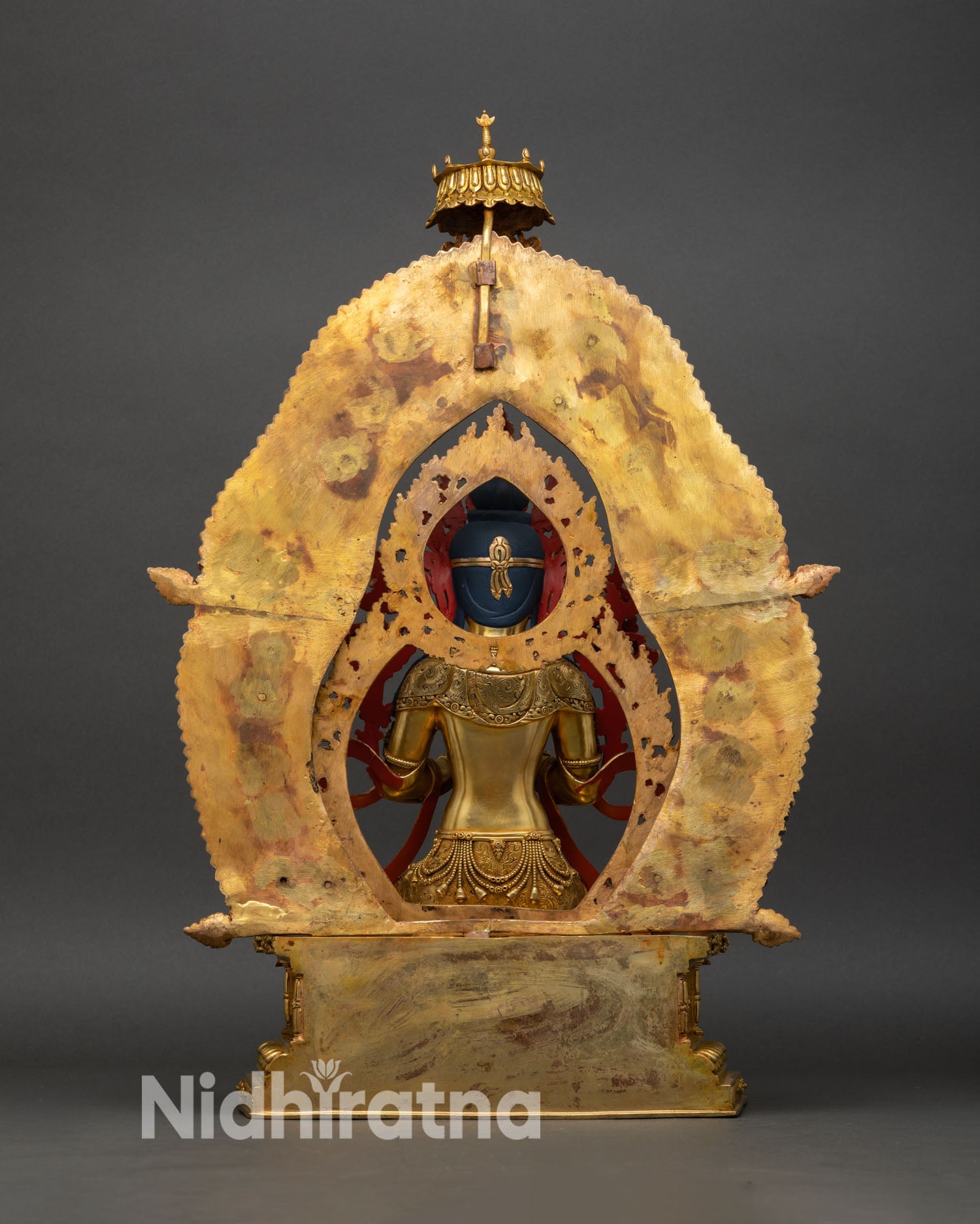 back view of maitreya buddha statue, flame halo with celestial carvings