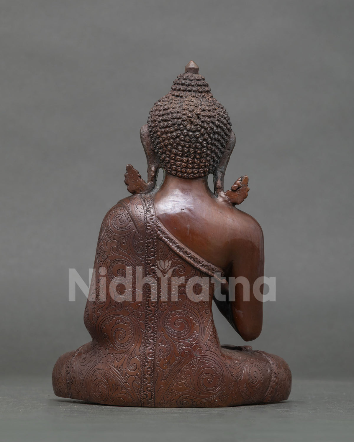 Back view of oxidized copper Amoghasiddhi Buddha statue showing carved robe and ushnisha