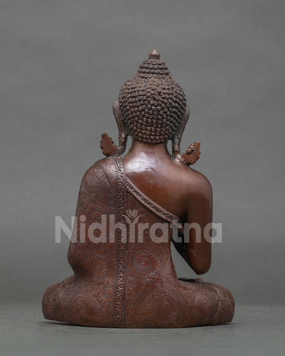 Back view of oxidized copper Amoghasiddhi Buddha statue showing carved robe and ushnisha