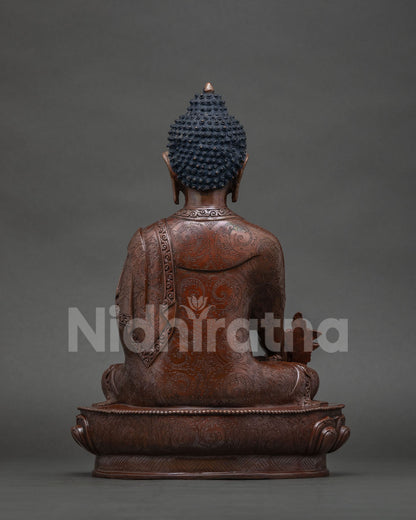 Back view of oxidized copper Medicine Buddha sculpture with intricate robe details.