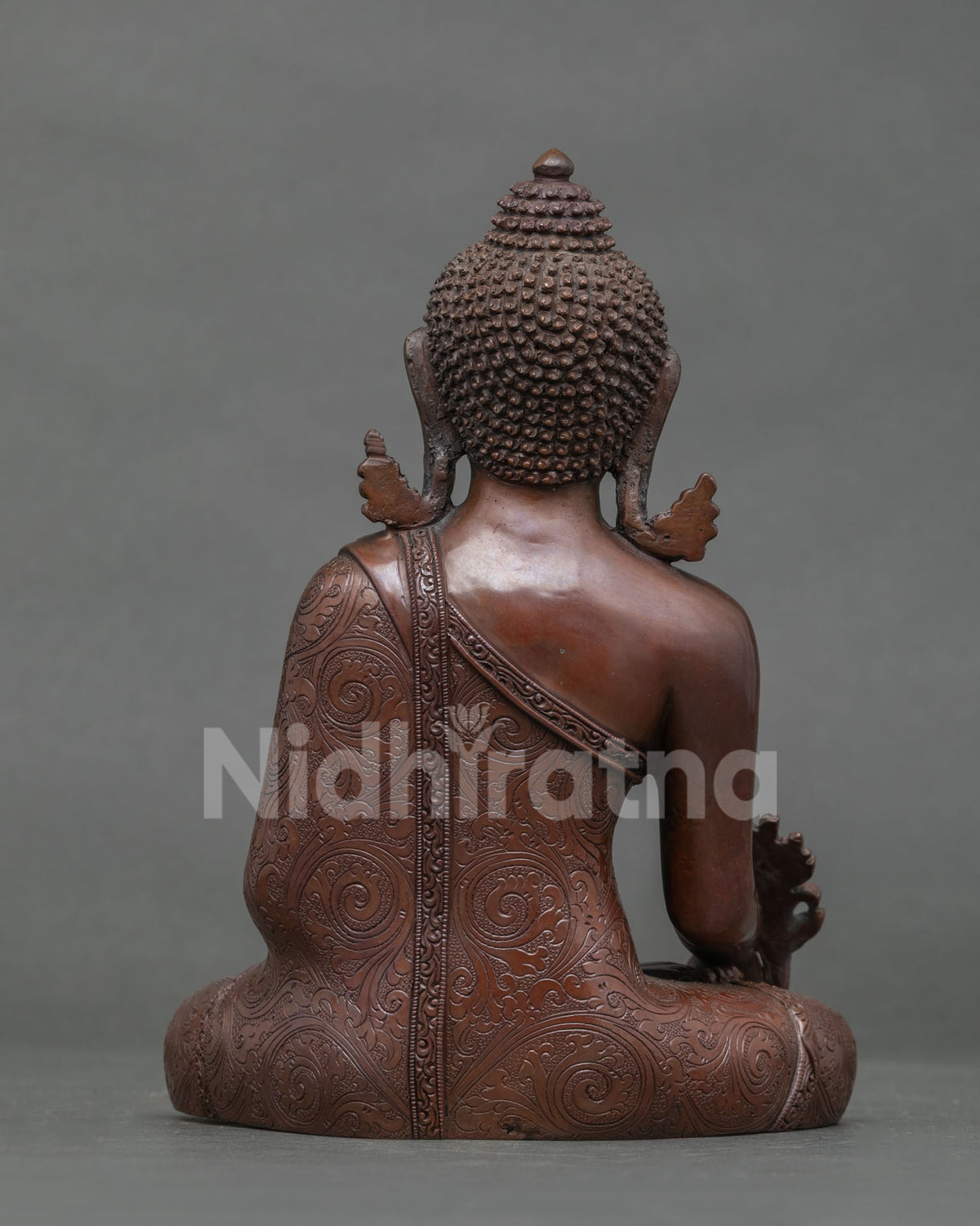 Back view of oxidized copper Medicine Buddha statue showing carved robe and ushnisha