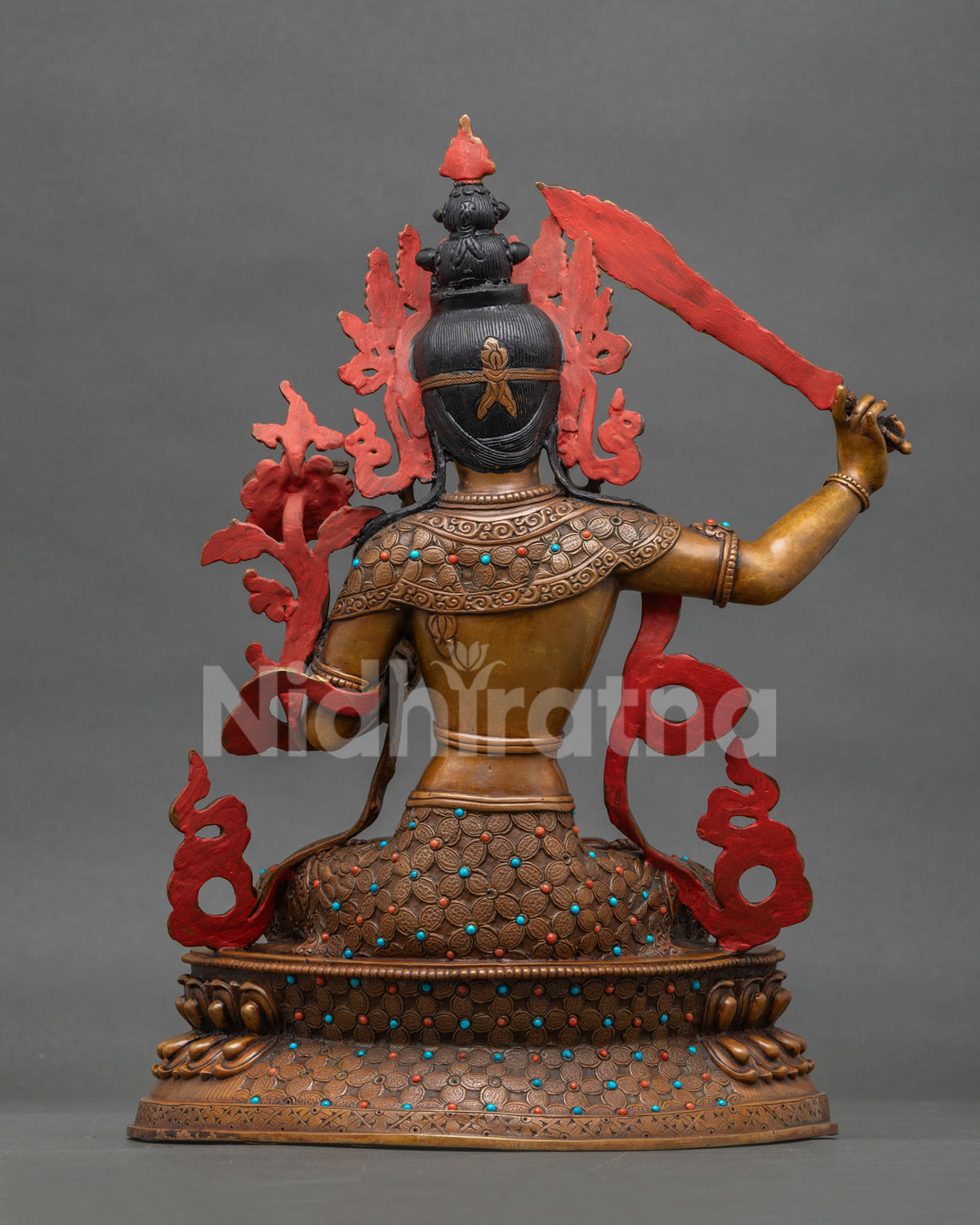 Back view of oxidized Manjushri copper statue showing gemstone-set robe and lotus base