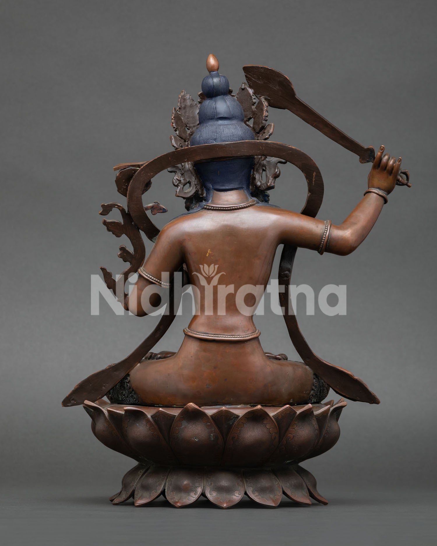 back view of oxidized manjushri statue with intricate copper engraving and lotus seat