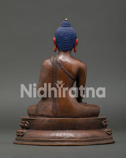 Back view of Shakyamuni Buddha statue highlighting oxidized copper finish and handcrafted robe details.
