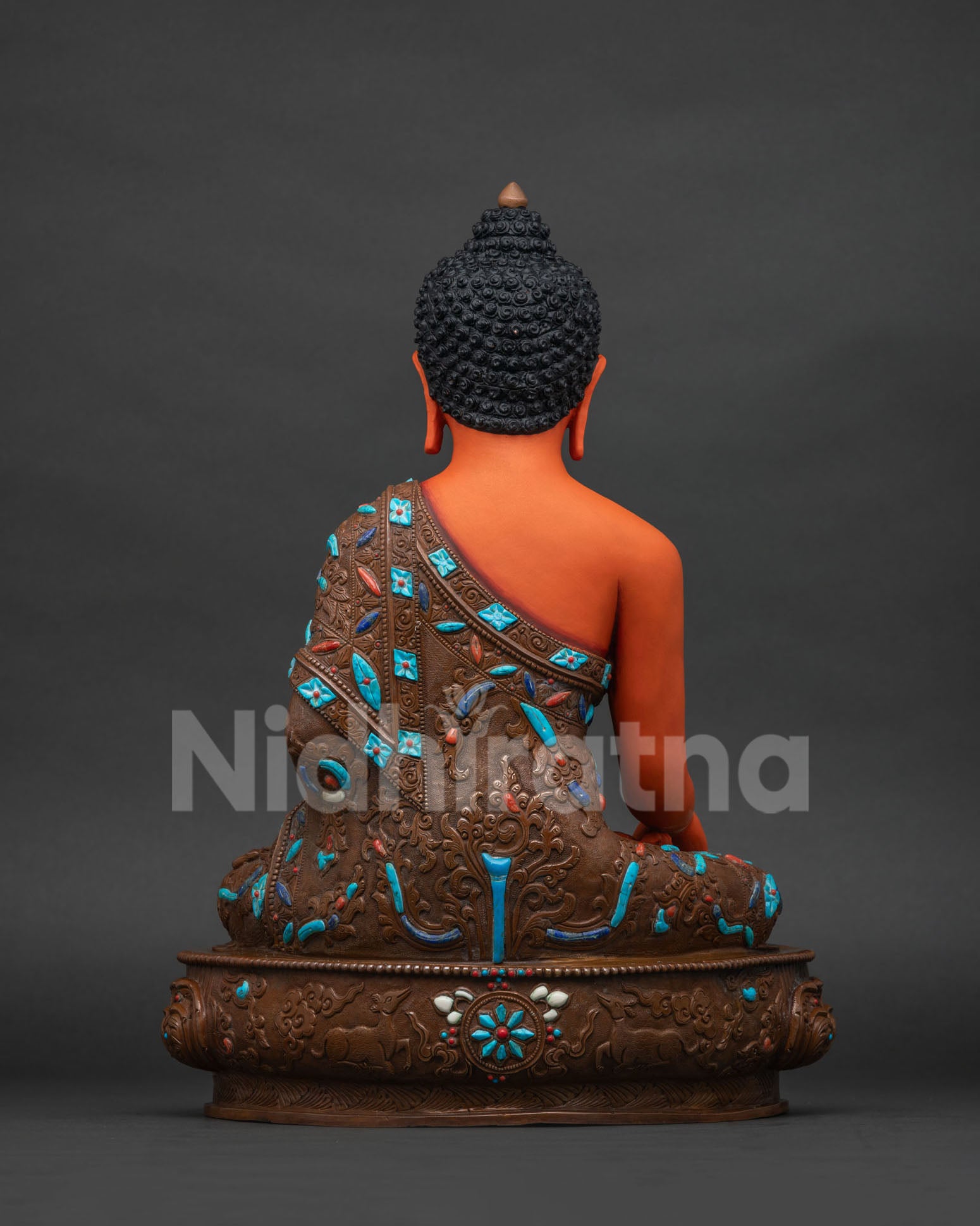Back view of Shakyamuni Buddha statue showing oxidized copper finish and floral robe carving